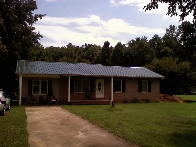 Dark green metal roof on a brick ranch with a covered porch in Cornwall