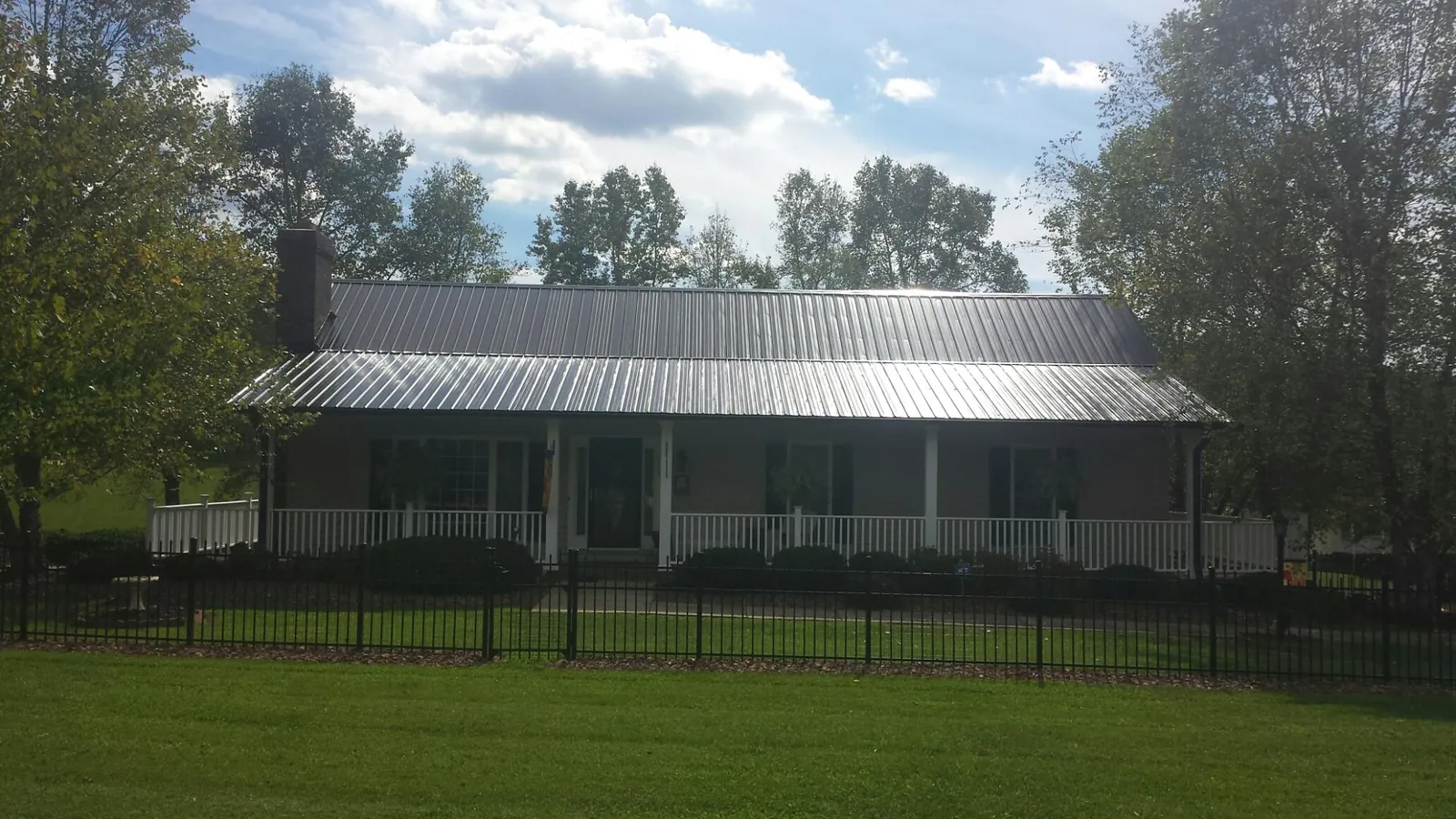 Gray metal roof on a brick ranch with a full width front porch — Gutter Guard Installation work by our crew in Cornwall